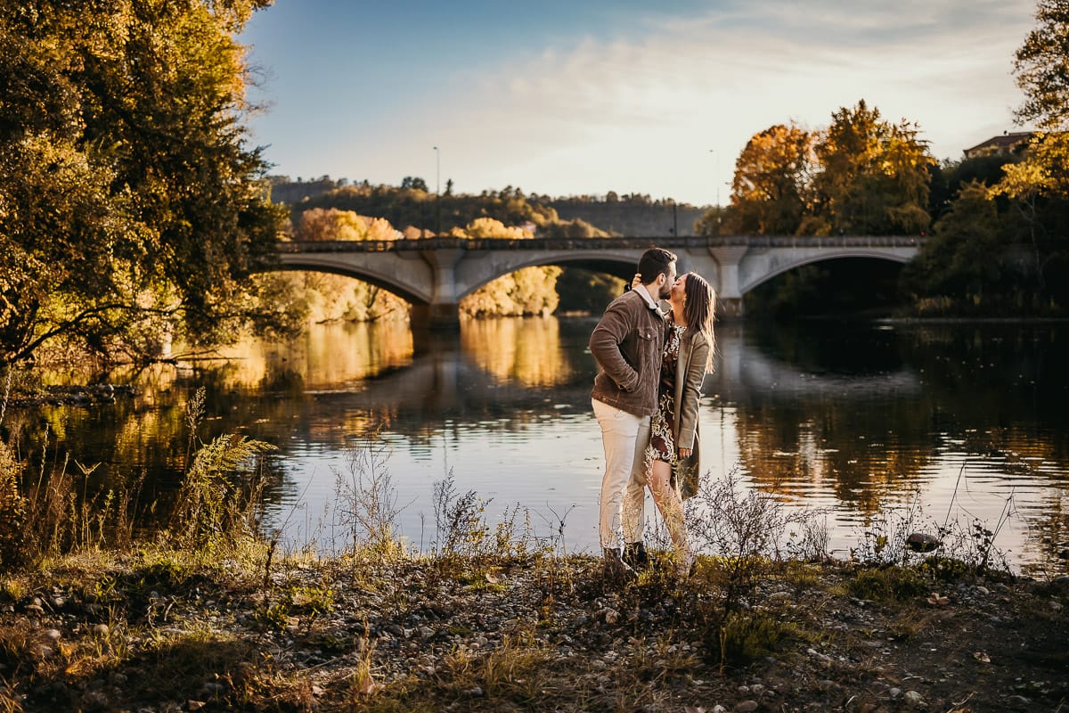 Prewedding a Torino, sul lungo Po al tramonto. Ritratto sulla riva del fiume con la magia dell'autunno sull'acqua. Sullo sfondo il ponte