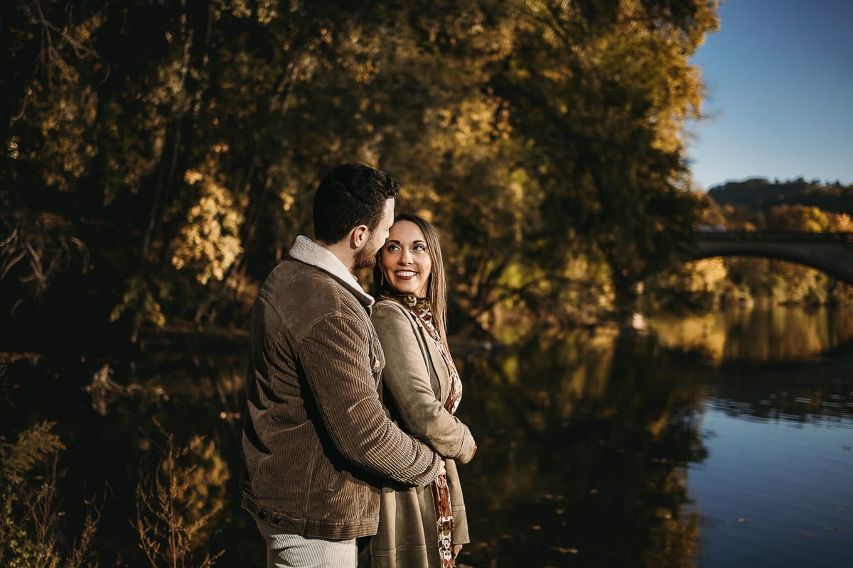 Prewedding a Torino, sul lungo Po al tramonto. Ritratto sulla riva del fiume con la magia dell'autunno sull'acqua. Sullo sfondo il ponte