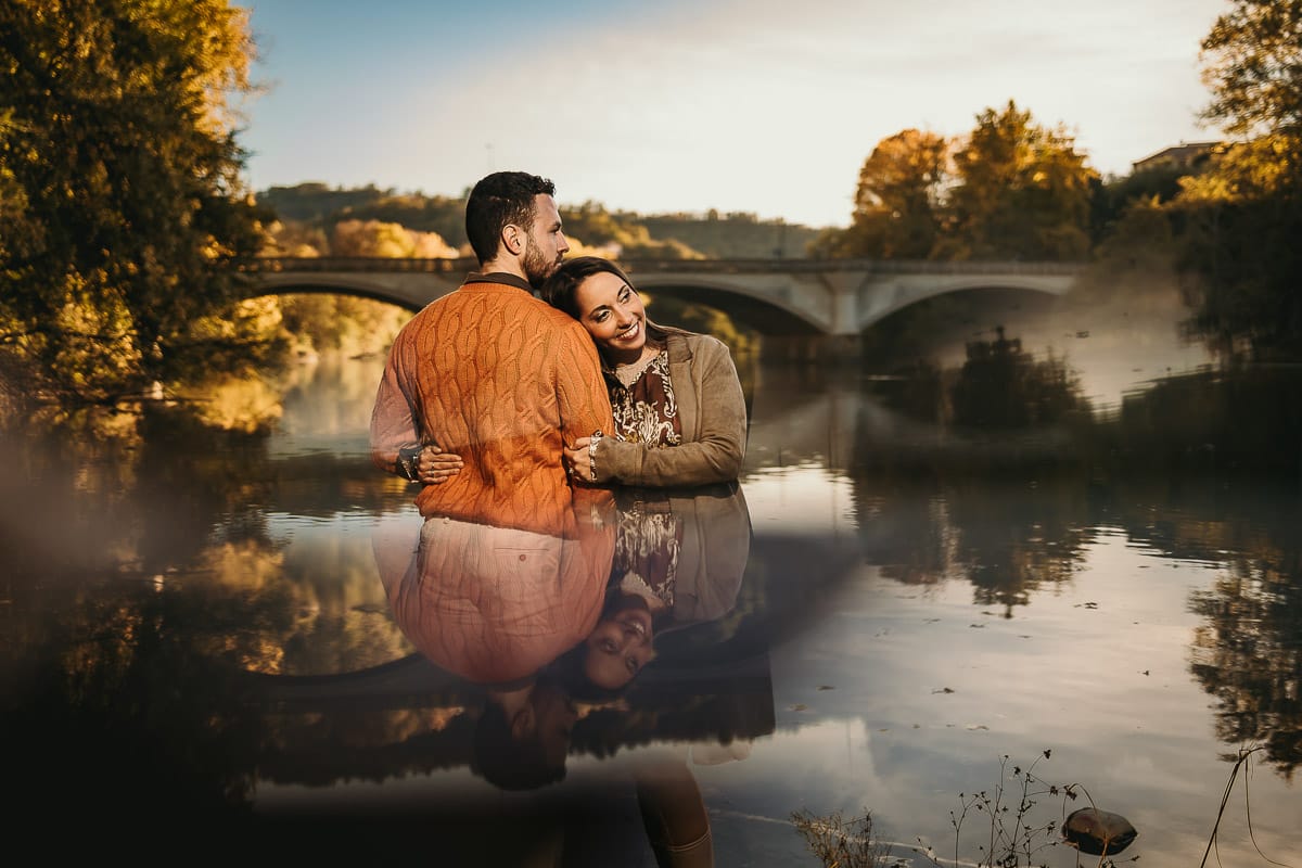 Prewedding a Torino, sul lungo Po al tramonto. Ritratto sulla riva del fiume con la magia dell'autunno sull'acqua. Sullo sfondo il ponte