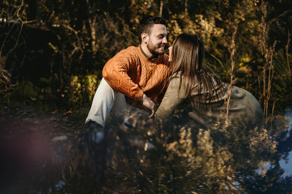 Prewedding a Torino, sul lungo Po al tramonto. Ritratto sulla riva del fiume con la magia dell'autunno sull'acqua. Coppia seduta