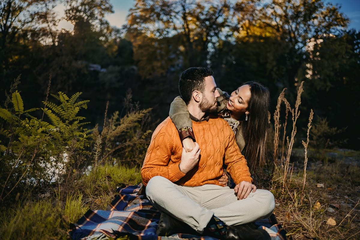 Prewedding a Torino, sul lungo Po al tramonto. Ritratto sulla riva del fiume con la magia dell'autunno sull'acqua. Coppia seduta