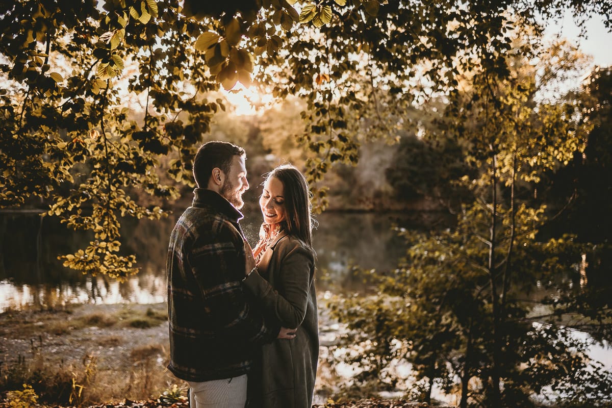 Prewedding a Torino, sul lungo Po al tramonto. Ritratto sulla riva del fiume con la magia dell'autunno sull'acqua. Coppia in controluce. Flare.
