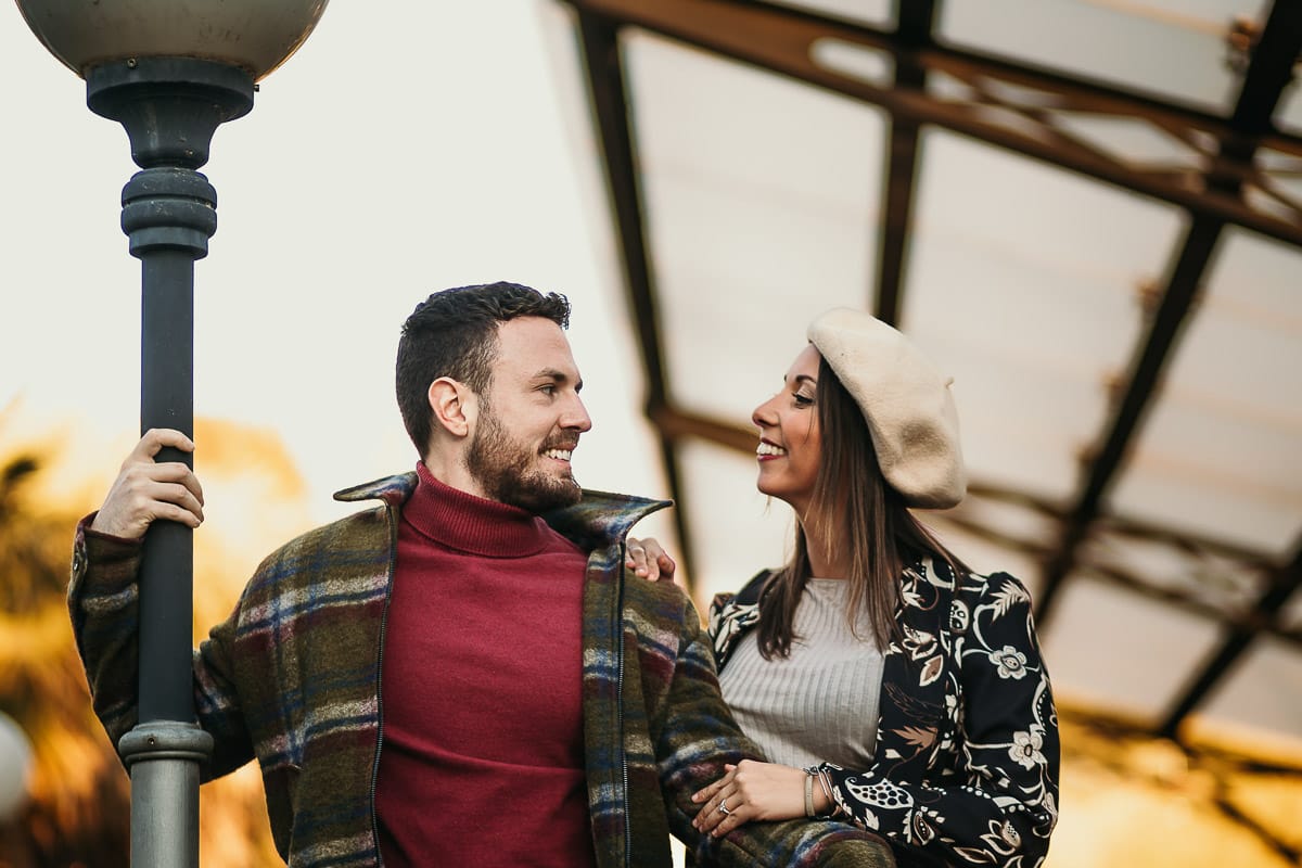 Prewedding a Torino, nella stazione di Sassi. Coppia seduta sul cancelletto di ferro davanti ai trenini a cremagliera che portano a Superga