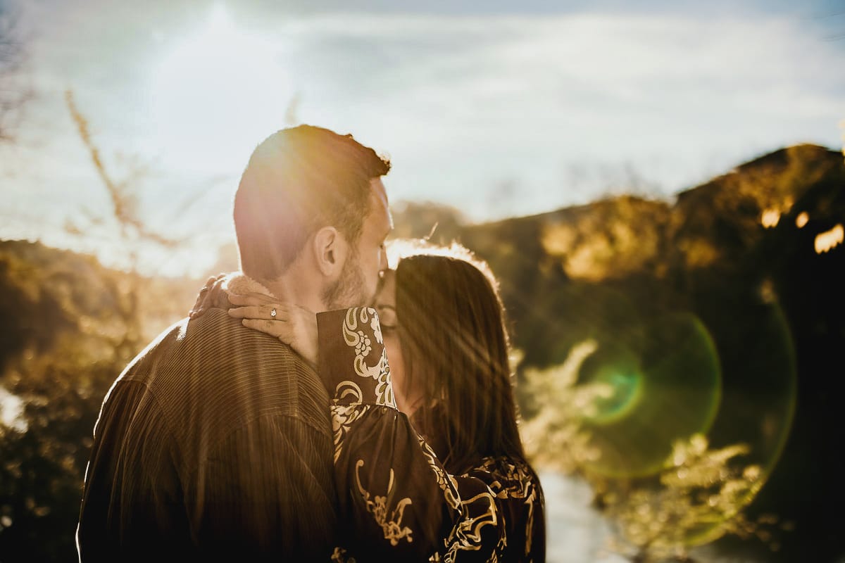 Prewedding a Torino, sul lungo Po al tramonto. Ragazzo bacia la ragazza sulla fronte. Flare.
