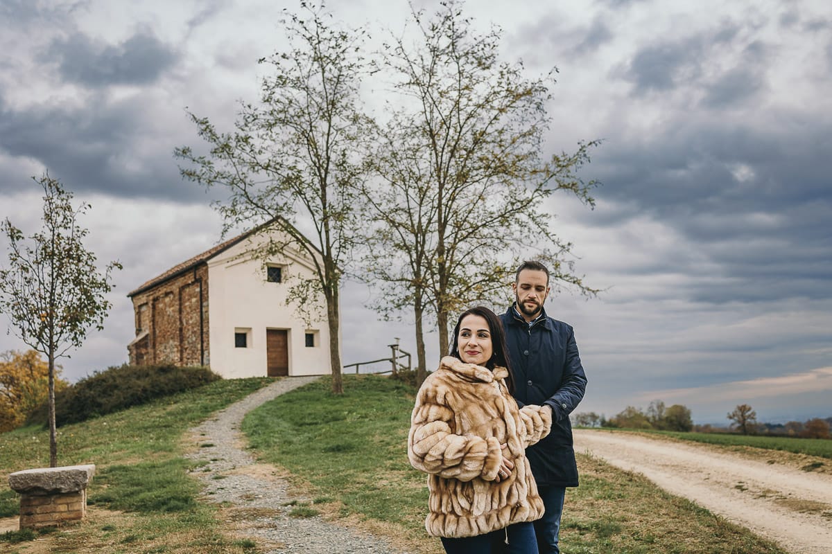 Fotografia di coppia invernale presso la chiesa di San Lorenzo di Mombello di Torino. Barbara e Riccardo camminano davanti alla chiesetta
