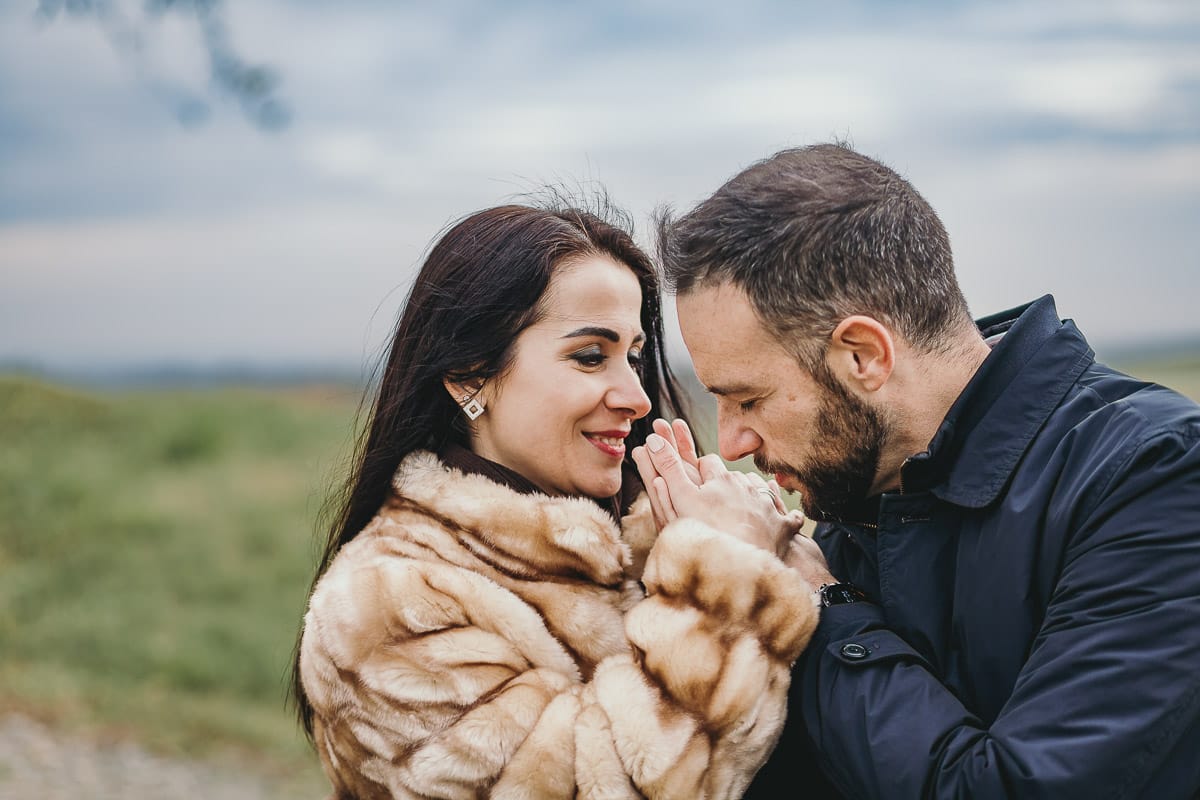 Fotografia di coppia invernale presso la chiesa di San Lorenzo di Mombello di Torino. Riccardo prende le mani di Barbara e le bacia