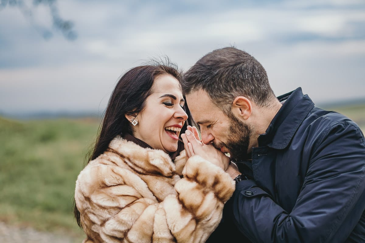 Fotografia di coppia invernale presso la chiesa di San Lorenzo di Mombello di Torino. Riccardo prende le mani di Barbara e le bacia