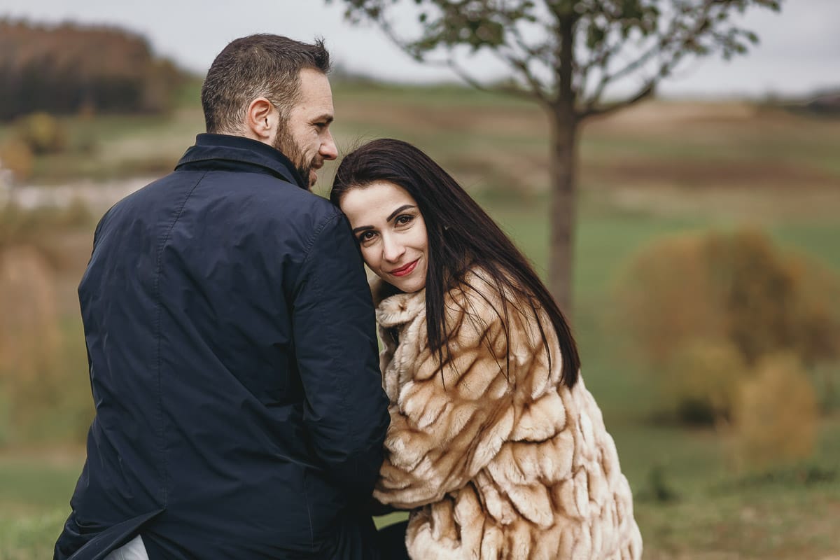 Fotografia di coppia invernale presso la chiesa di San Lorenzo di Mombello di Torino. Barbara e Riccardo seduti su di una panchina di pietra davanti alla chiesetta di san Lorenzo
