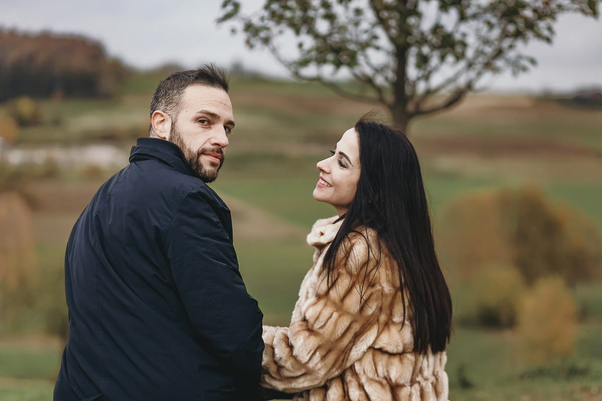 Fotografia di coppia invernale presso la chiesa di San Lorenzo di Mombello di Torino. Barbara e Riccardo seduti su di una panchina di pietra davanti alla chiesetta di san Lorenzo