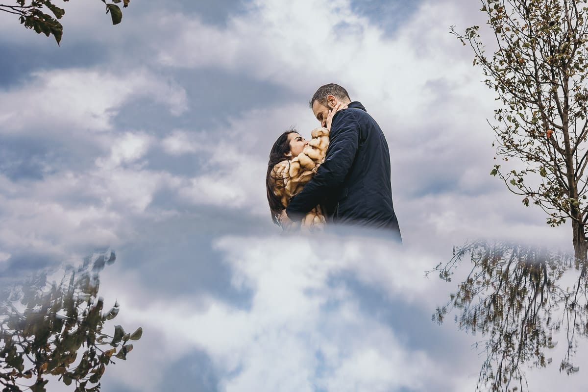 Fotografia di coppia invernale presso la chiesa di San Lorenzo di Mombello di Torino. Barbara e Riccardo tra le nuvole.Ritratto riflesso con un piccolo specchio