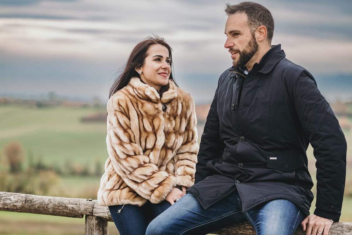Fotografia di coppia invernale presso la chiesa di San Lorenzo di Mombello di Torino. Barbara e Riccardo sono seduti su di una staccionata di legno
