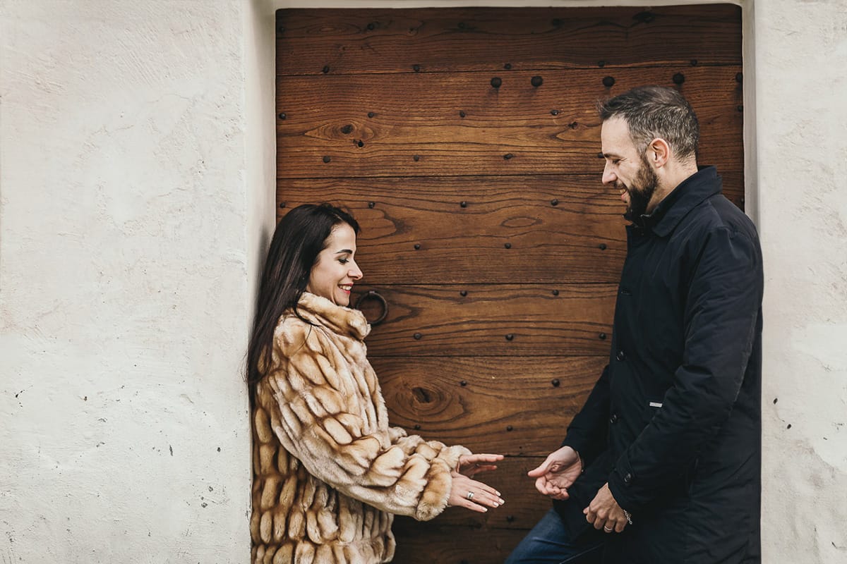 Fotografia di coppia invernale presso la chiesa di San Lorenzo di Mombello di Torino. Barbara e Riccardo davanti alla porta di legno della chiesetta