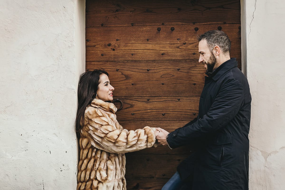 Fotografia di coppia invernale presso la chiesa di San Lorenzo di Mombello di Torino. Barbara e Riccardo davanti alla porta di legno della chiesetta
