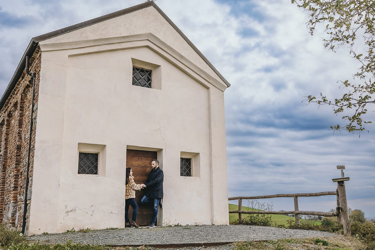 Fotografia di coppia invernale presso la chiesa di San Lorenzo di Mombello di Torino. Barbara e Riccardo davanti alla porta di legno della chiesetta