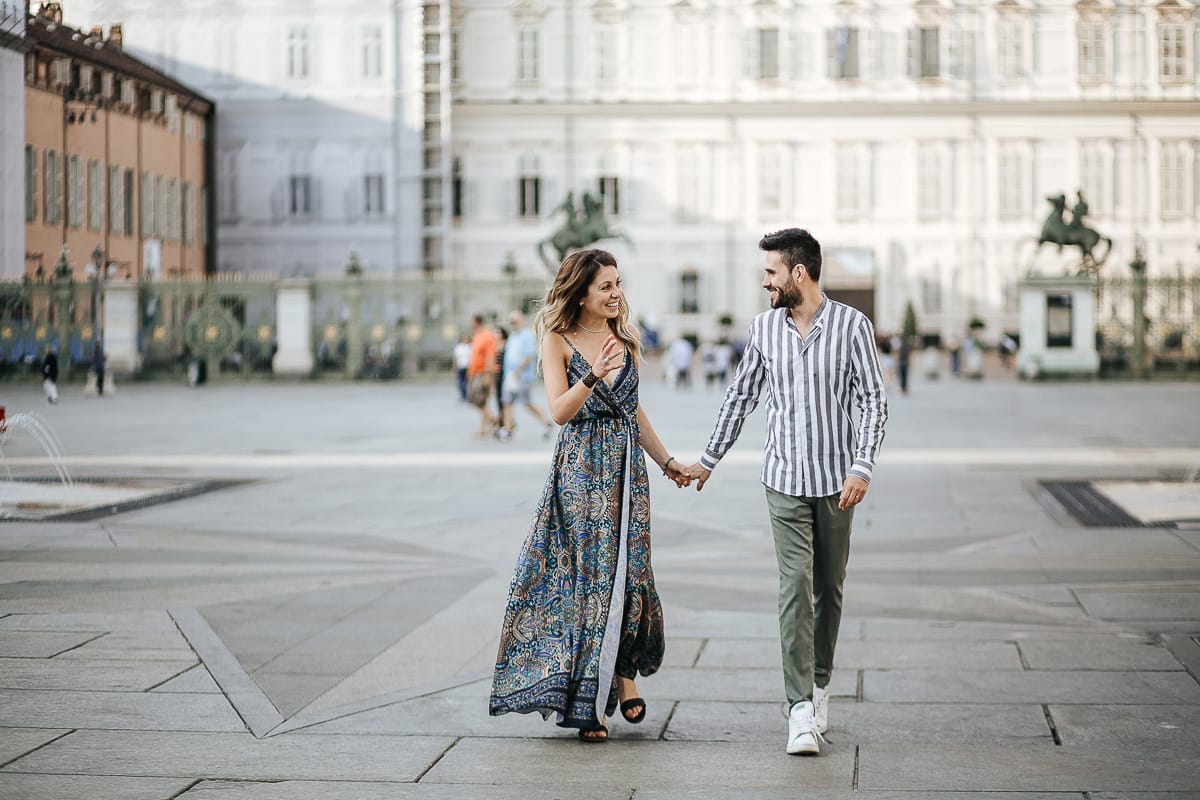 Prewedding nel centro di Torino Elisa e Davide camminano in piazza Castello davanti a Palazzo Reale