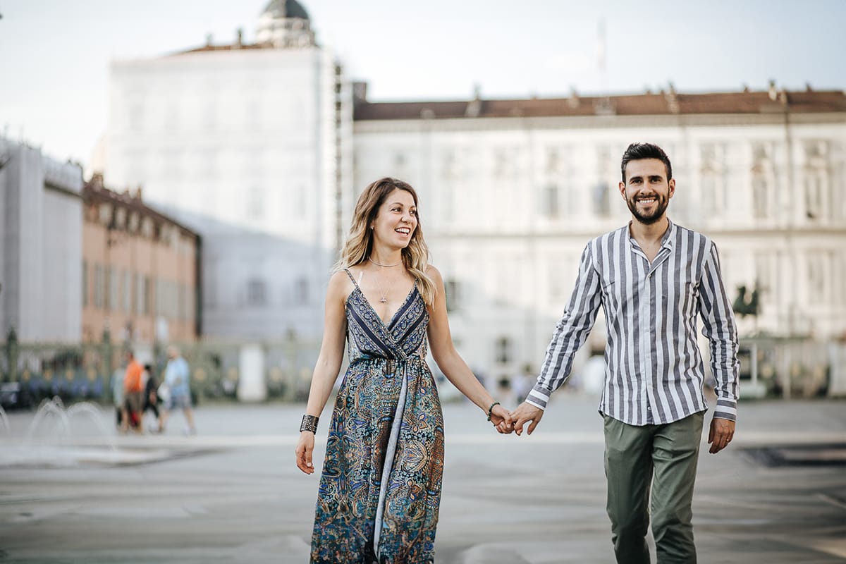 Prewedding nel centro di Torino Elisa e Davide camminano in piazza Castello davanti a Palazzo Reale