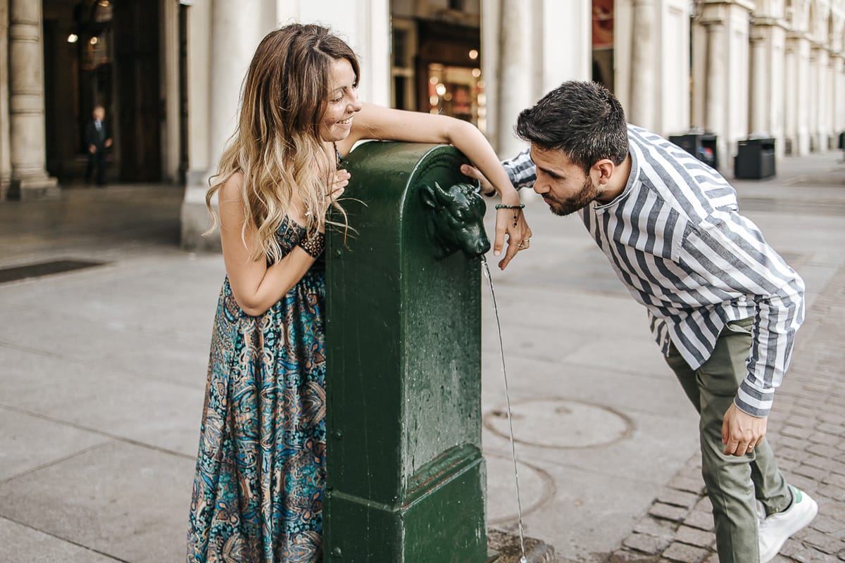 Prewedding nel centro di Torino Elisa e Davide in piazza San Carlo Elisa disturba Davide mentre cerca di bere ad una fontanella Turet