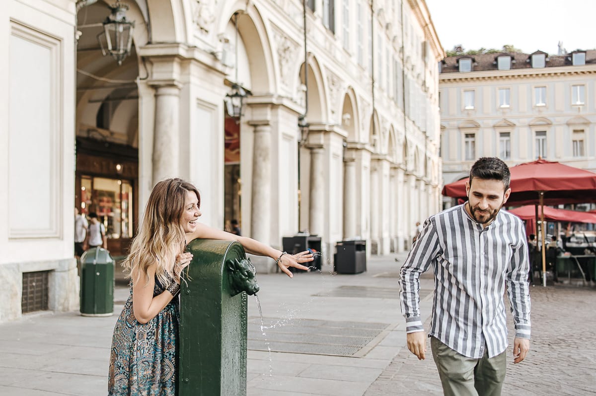 Prewedding nel centro di Torino Elisa e Davide in piazza san Carlo. Elisa spruzza Davide.