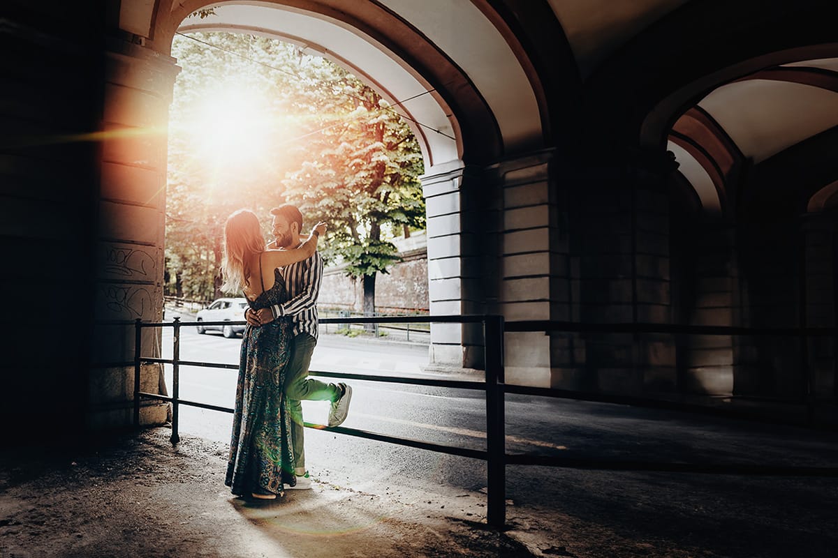 Prewedding nel centro di Torino Elisa e Davide si abbracciano in controluce con il sole che crea un flare in mezzo a loro.