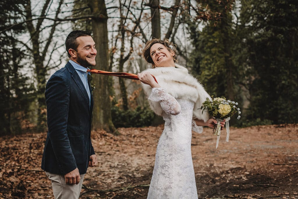 Winter wedding at the Superga hill park, among coniferous trees reminiscent of the great parks of North America. The bride pulls the groom by his tie.
