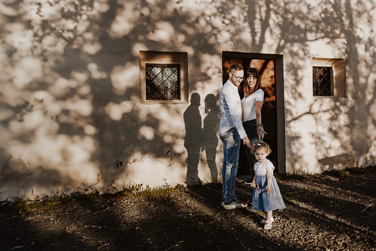 Ilenia e Filippo si stringono in un abbraccio d'amore, mentre i loro figli giocano felici al tramonto.