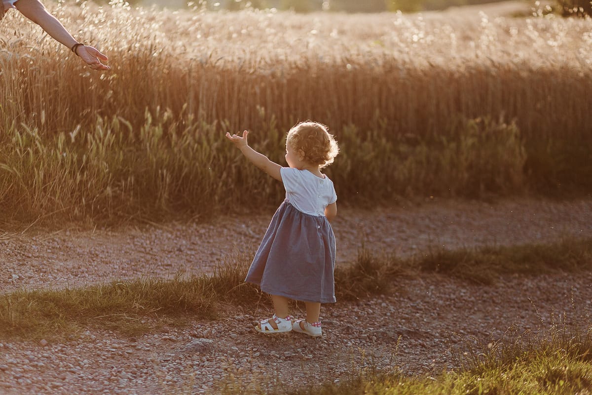 Fotografia di famiglia al tramonto. la piccola Camilla sta per prendere la mano della mamma.
