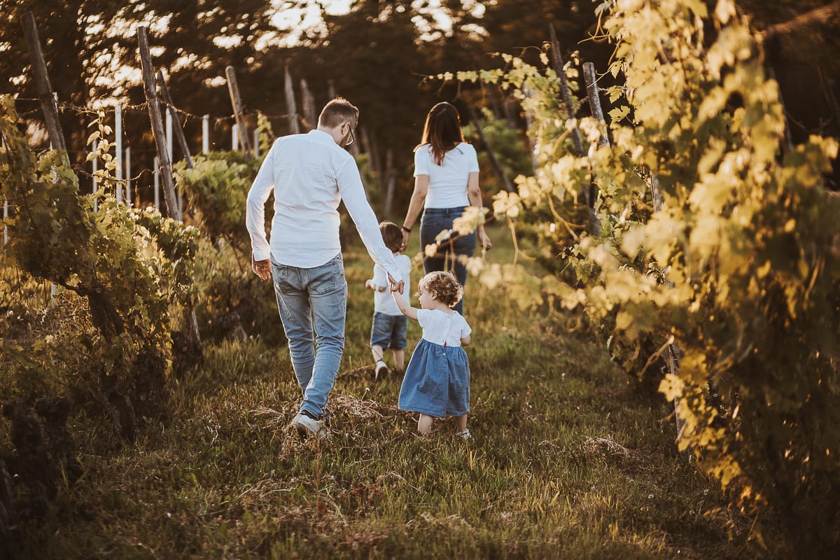 Ilenia e Filippo camminano mano nella mano con i loro figli, immersi nella luce dorata del tramonto.