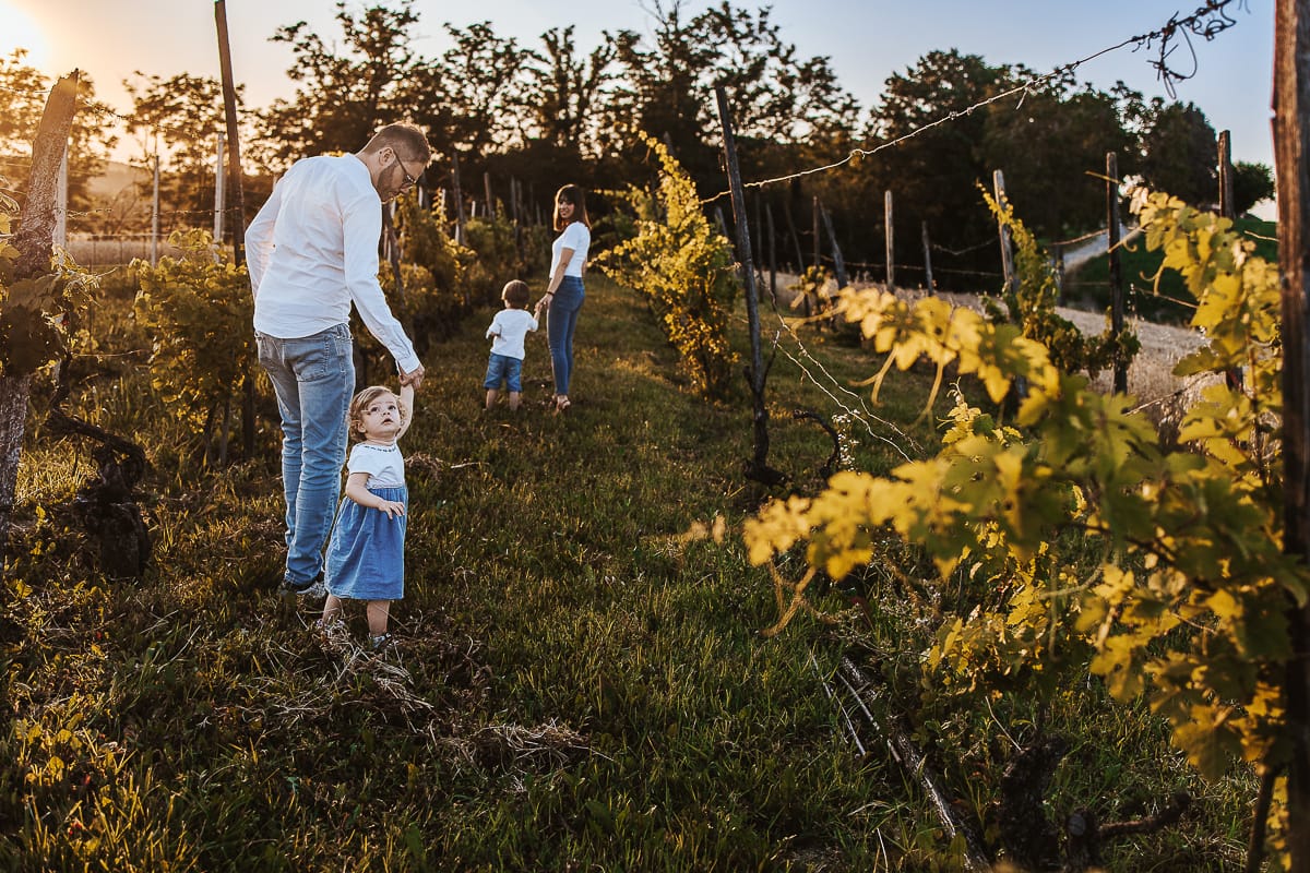 Ilenia e Filippo camminano mano nella mano con i loro figli, immersi nella luce dorata del tramonto.