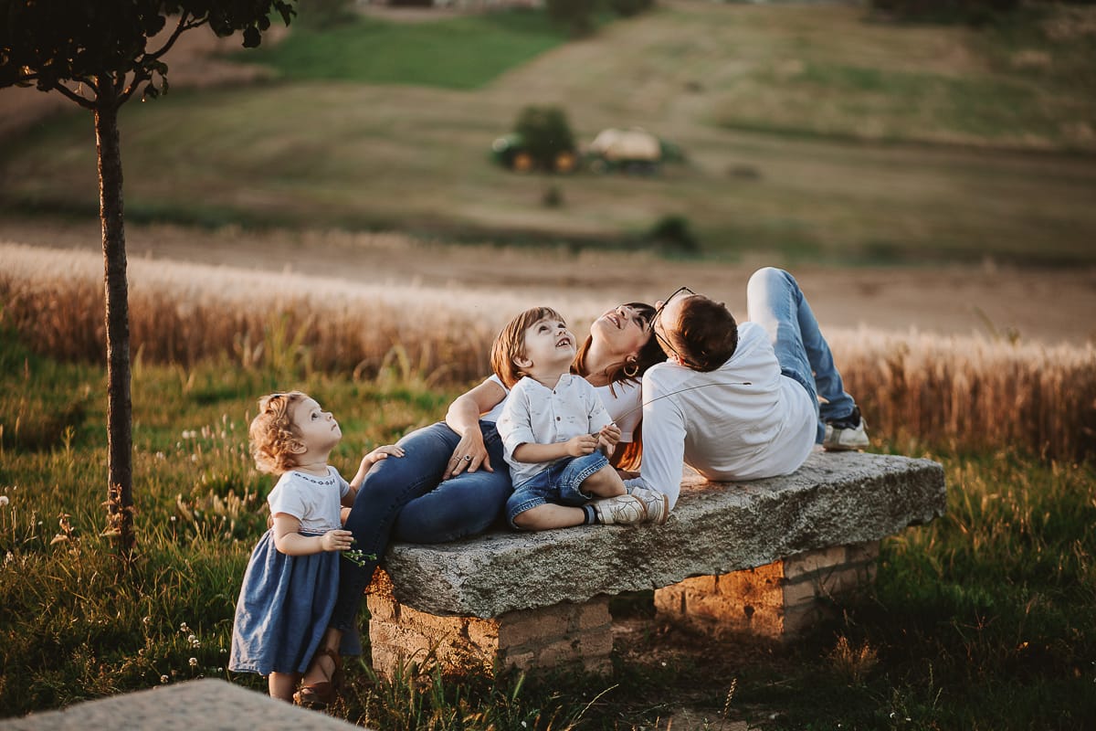 La famiglia si siede su una panchina e si gode la vista mozzafiato del tramonto. La piccola Camilla incuriosita dal drone.