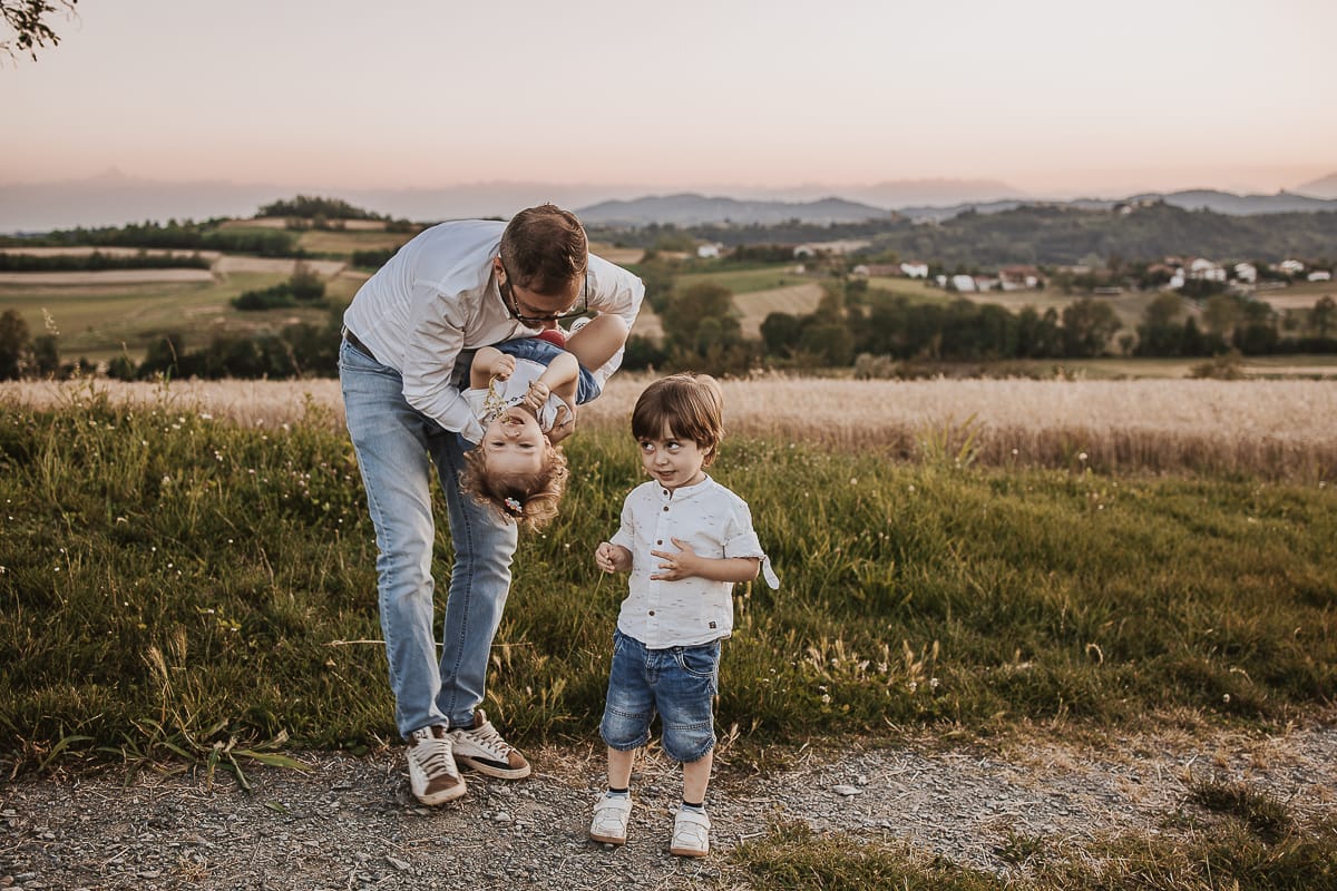 Fotografia di famiglia al tramonto. Il papà gioca con i figli.
