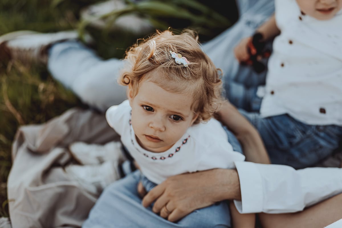 Foto di Famiglia al Tramonto: Ilenia, Filippo, Edoardo e Camilla a Mombello di Torino. la famiglia sdraiata nel sentiero in mezzo a due campi di grano. I bambini sono incuriositi dal drone.