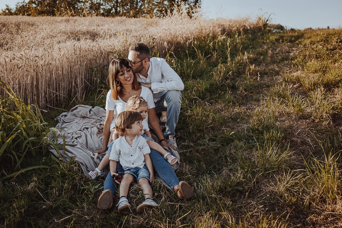 Foto di Famiglia al Tramonto: Ilenia, Filippo, Edoardo e Camilla a Mombello di Torino. la famiglia seduta in un sentiero tra due campi di grano.