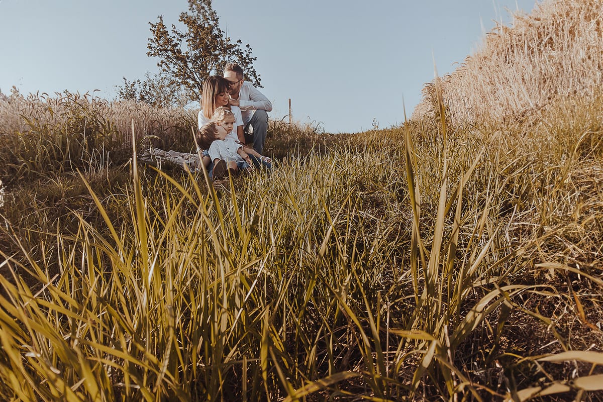 Foto di Famiglia al Tramonto: Ilenia, Filippo, Edoardo e Camilla a Mombello di Torino. la famiglia seduta in un sentiero tra due campi di grano. Foto ripresa dal drone posato per terra.