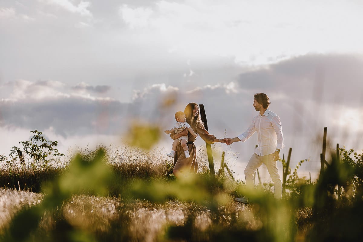 Servizio fotografico di famiglia a Torino: un tramonto dorato a Mombello di Torino. Chiara, Alessandro e il piccolo Leonardo camminano