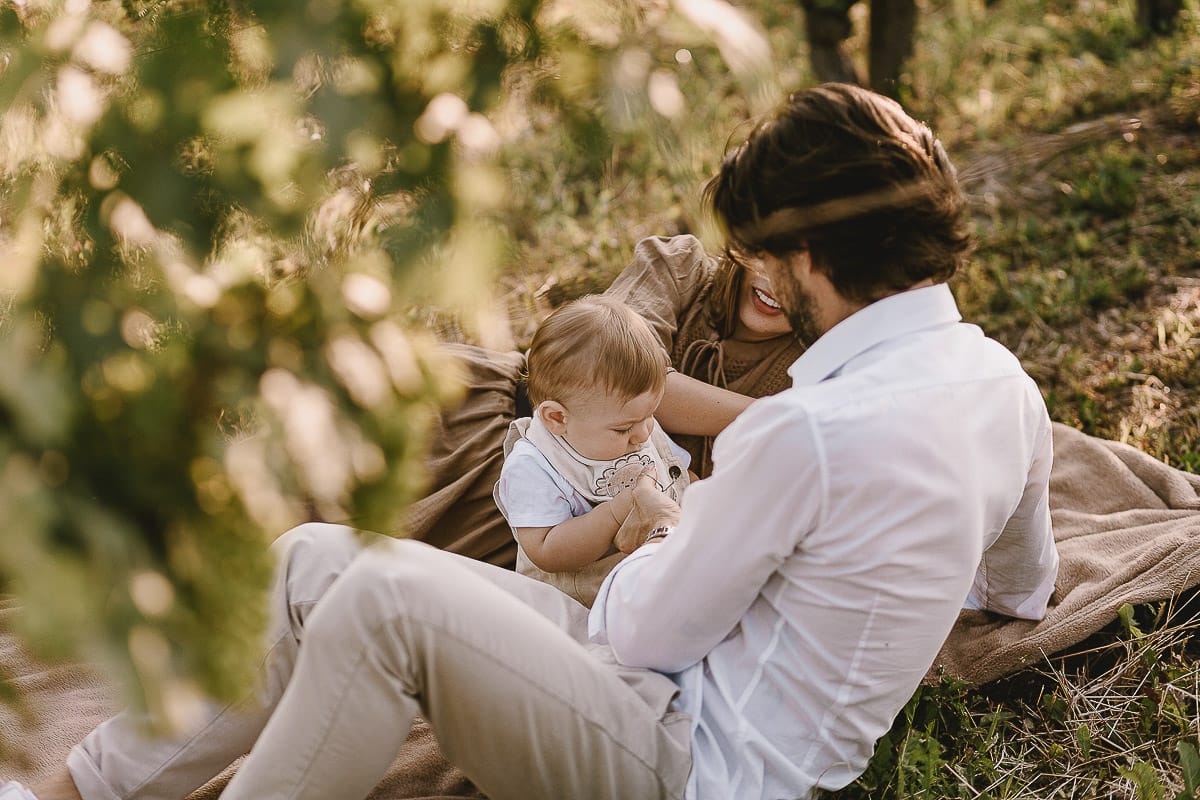 Servizio fotografico di famiglia a Torino: un tramonto dorato a Mombello di Torino. Chiara, Alessandro e il piccolo Leonardo sdraiati in un vigneto