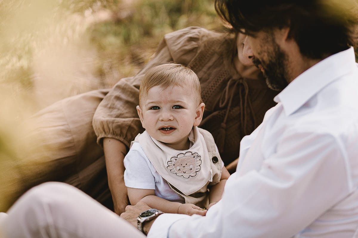 Servizio fotografico di famiglia a Torino: un tramonto dorato a Mombello di Torino. Chiara, Alessandro e il piccolo Leonardo sdraiati in un vigneto