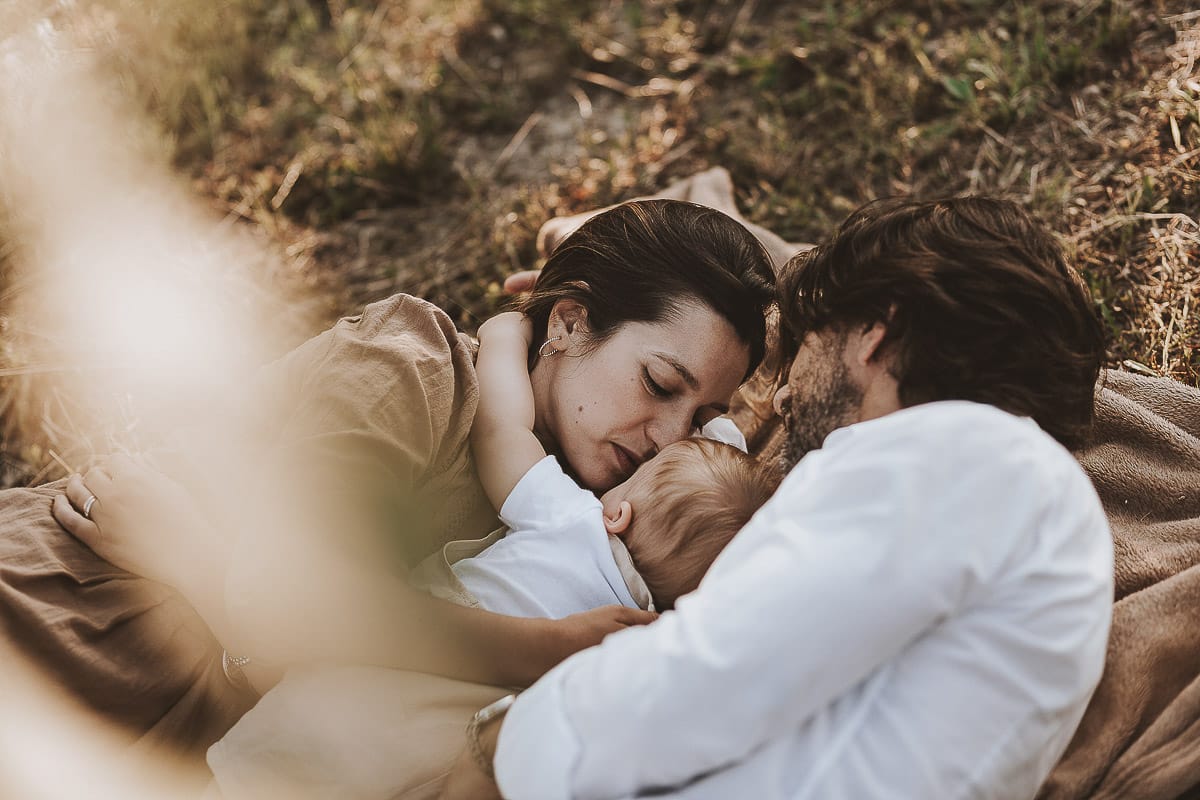 Servizio fotografico di famiglia a Torino: un tramonto dorato a Mombello di Torino. Chiara, Alessandro e il piccolo Leonardo sdraiati in un vigneto