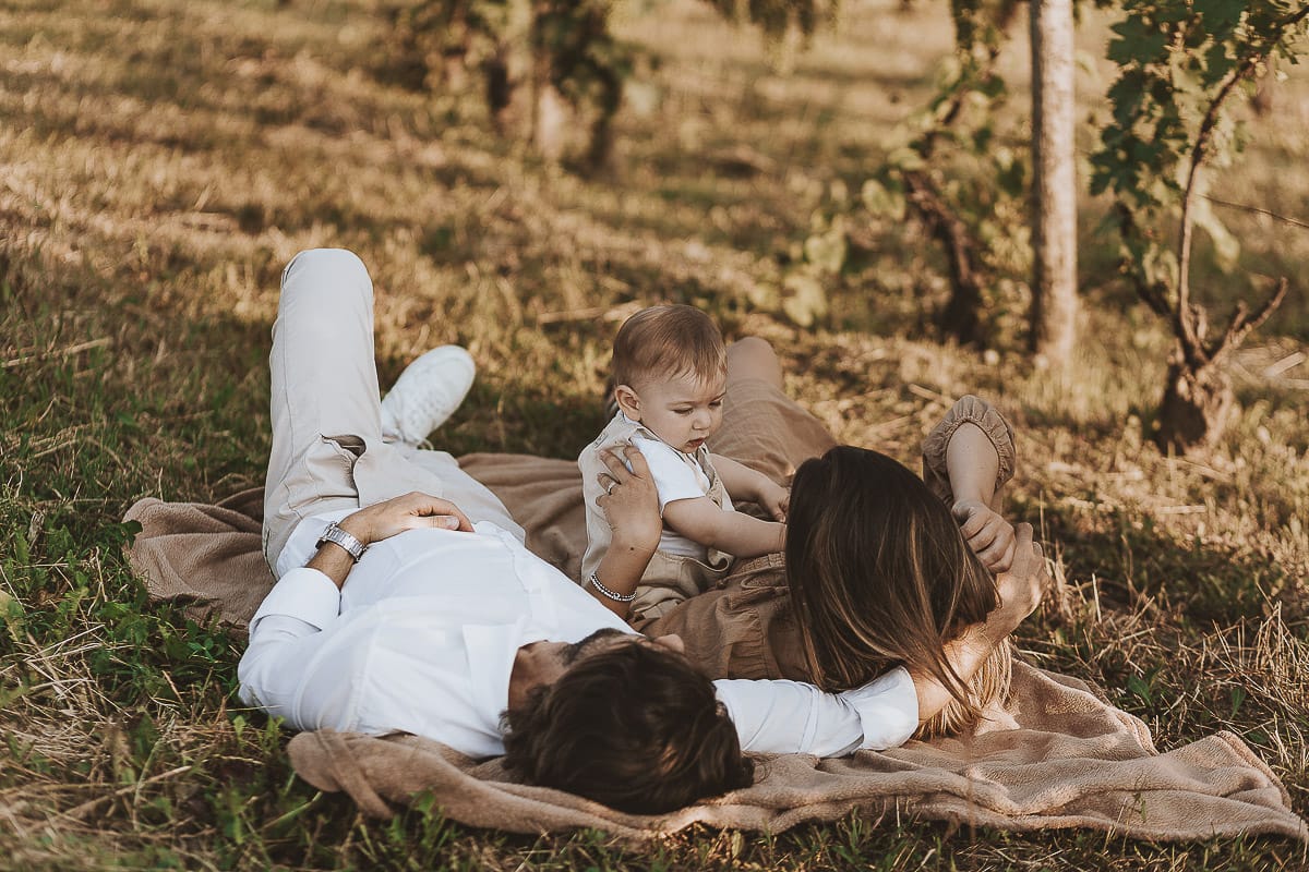 Servizio fotografico di famiglia a Torino: un tramonto dorato a Mombello di Torino. Chiara, Alessandro e il piccolo Leonardo sdraiati in un vigneto
