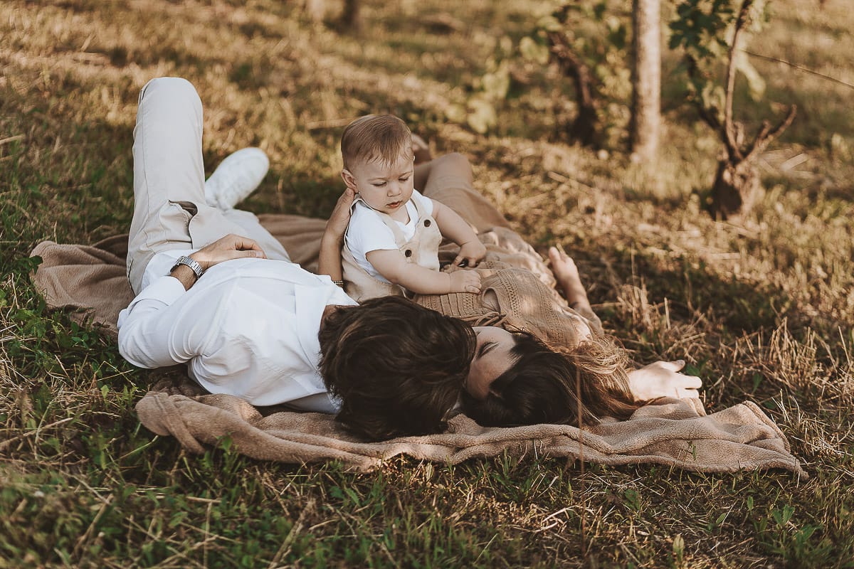 Servizio fotografico di famiglia a Torino: un tramonto dorato a Mombello di Torino. Chiara, Alessandro e il piccolo Leonardo sdraiati in un vigneto
