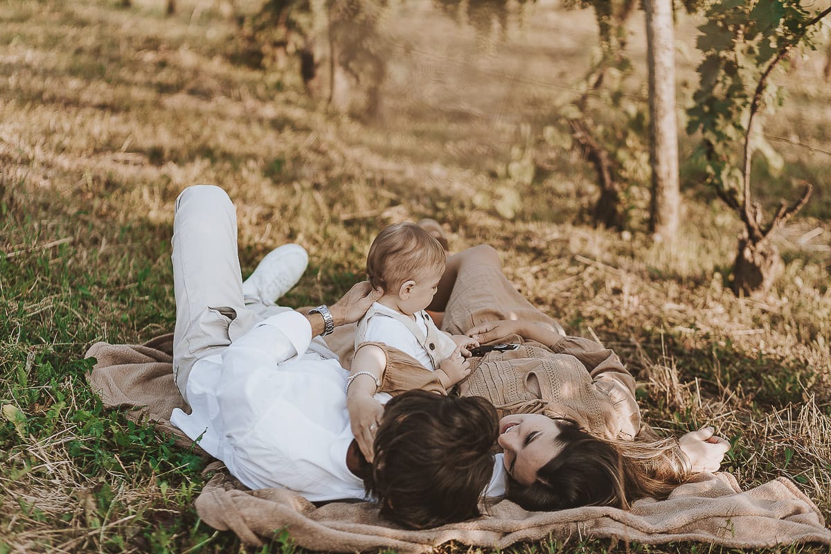 Servizio fotografico di famiglia a Torino: un tramonto dorato a Mombello di Torino. Chiara, Alessandro e il piccolo Leonardo sdraiati in un vigneto