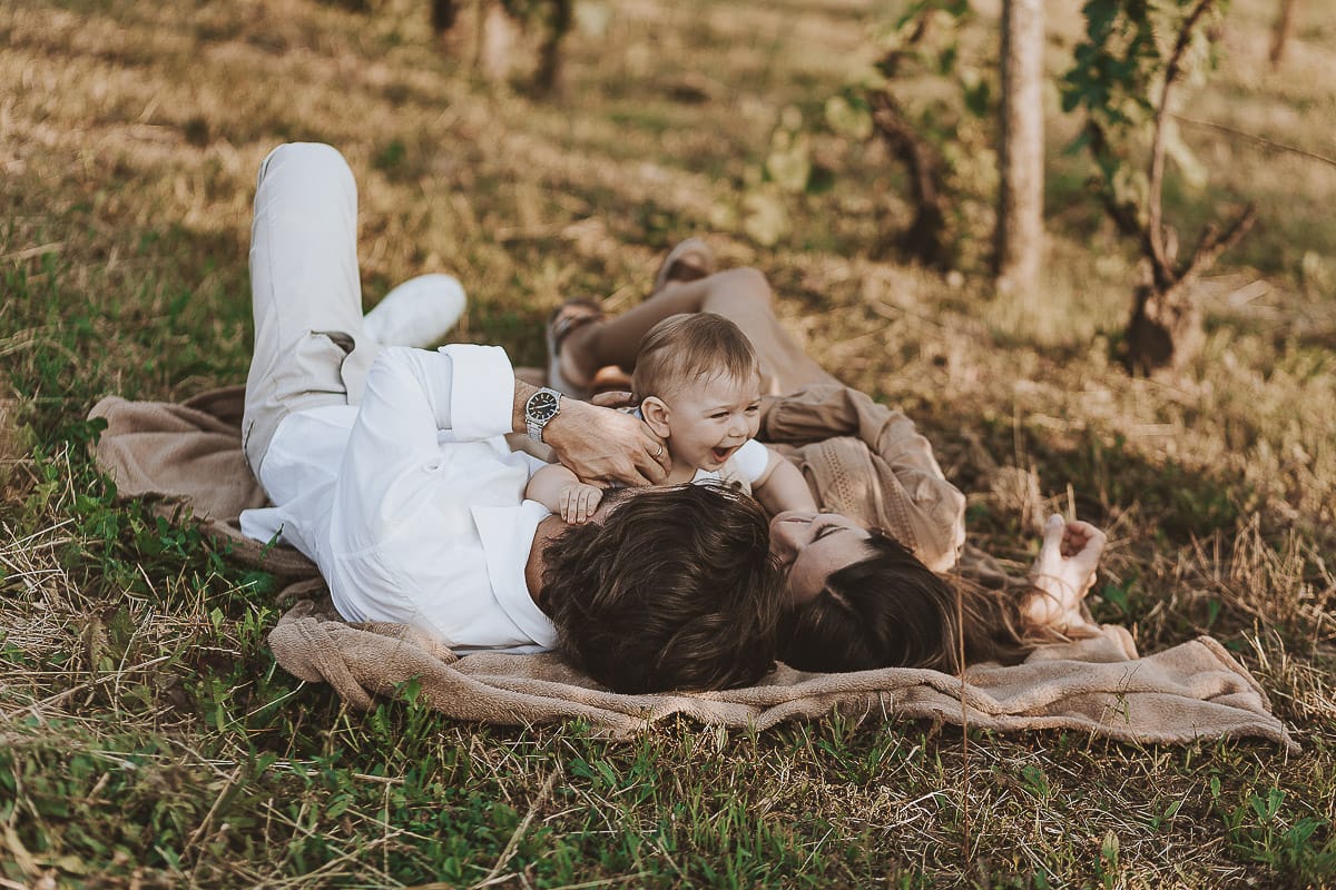Servizio fotografico di famiglia a Torino: un tramonto dorato a Mombello di Torino. Chiara, Alessandro e il piccolo Leonardo sdraiati in un vigneto