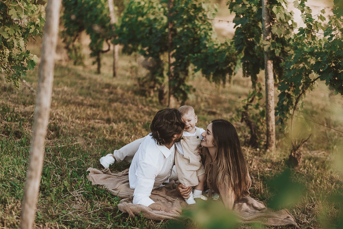 Servizio fotografico di famiglia a Torino: un tramonto dorato a Mombello di Torino. Chiara, Alessandro e il piccolo Leonardo sdraiati in un vigneto
