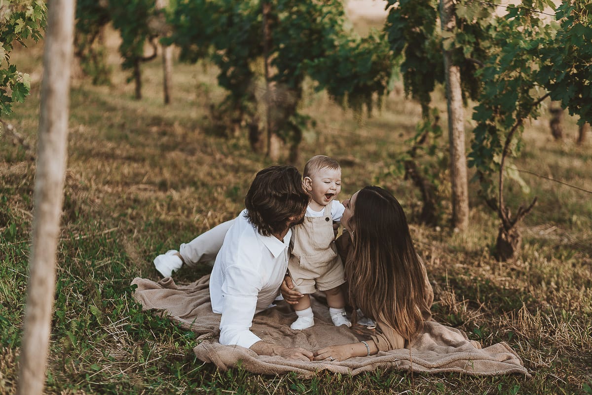 Servizio fotografico di famiglia a Torino: un tramonto dorato a Mombello di Torino. Chiara, Alessandro e il piccolo Leonardo sdraiati in un vigneto