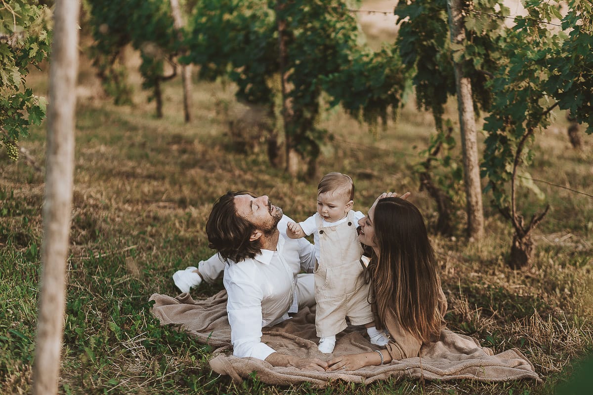 Servizio fotografico di famiglia a Torino: un tramonto dorato a Mombello di Torino. Chiara, Alessandro e il piccolo Leonardo sdraiati in un vigneto