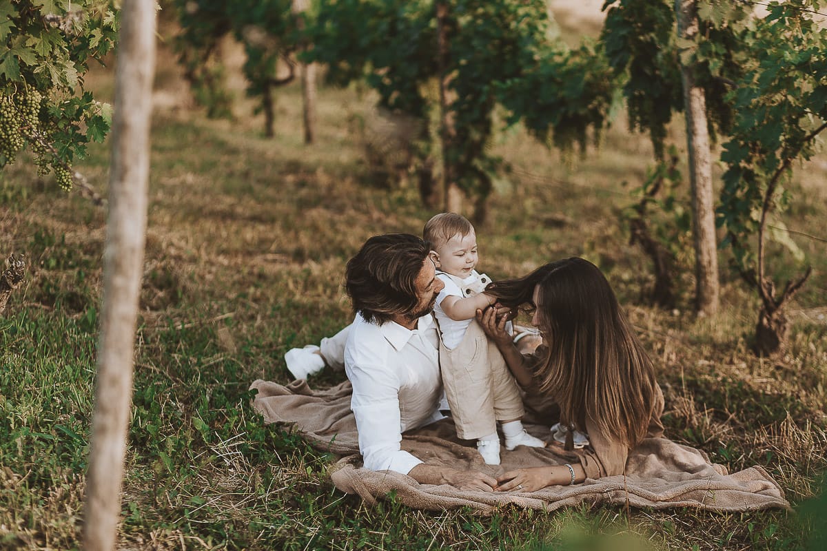 Servizio fotografico di famiglia a Torino: un tramonto dorato a Mombello di Torino. Chiara, Alessandro e il piccolo Leonardo sdraiati in un vigneto