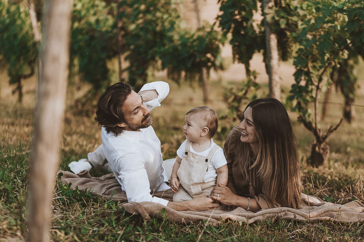 Servizio fotografico di famiglia a Torino: un tramonto dorato a Mombello di Torino. Chiara, Alessandro e il piccolo Leonardo sdraiati in un vigneto