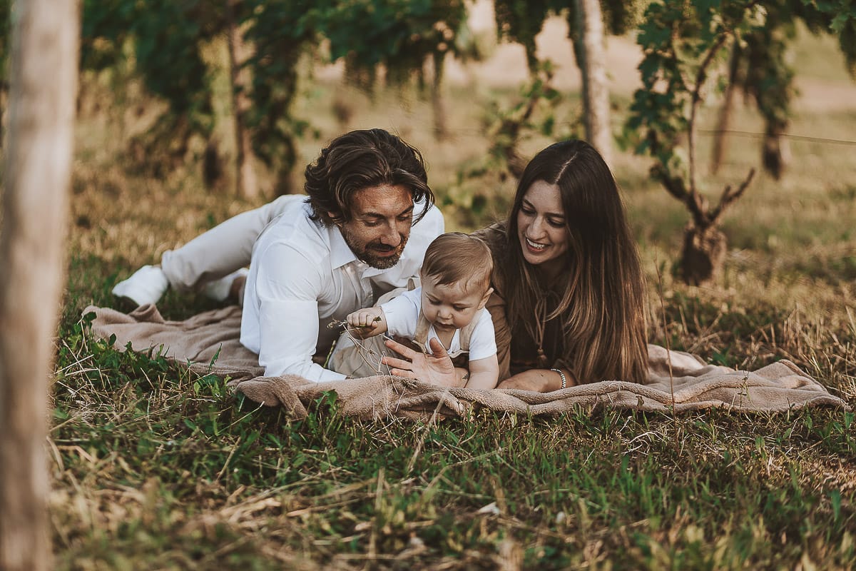 Servizio fotografico di famiglia a Torino: un tramonto dorato a Mombello di Torino. Chiara, Alessandro e il piccolo Leonardo sdraiati in un vigneto