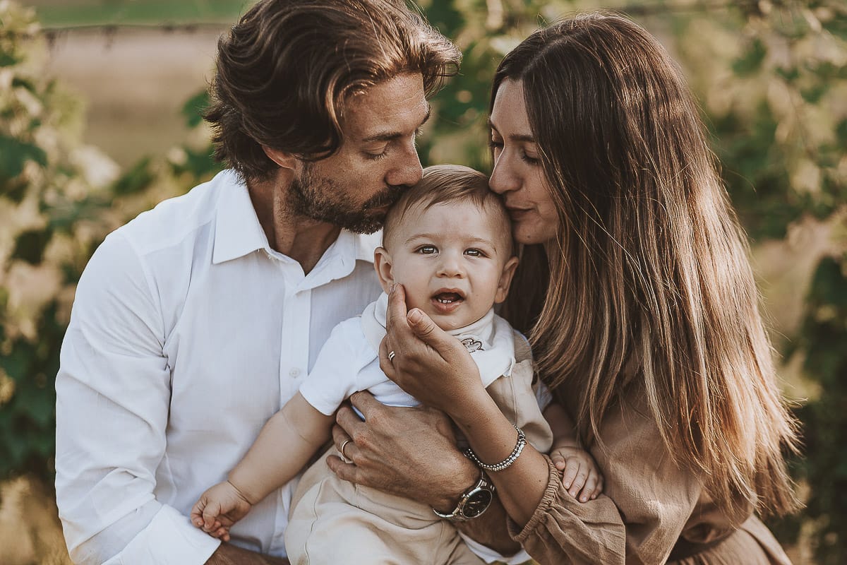 Servizio fotografico di famiglia a Torino: un tramonto dorato a Mombello di Torino. Chiara, Alessandro e il piccolo Leonardo sdraiati in un vigneto