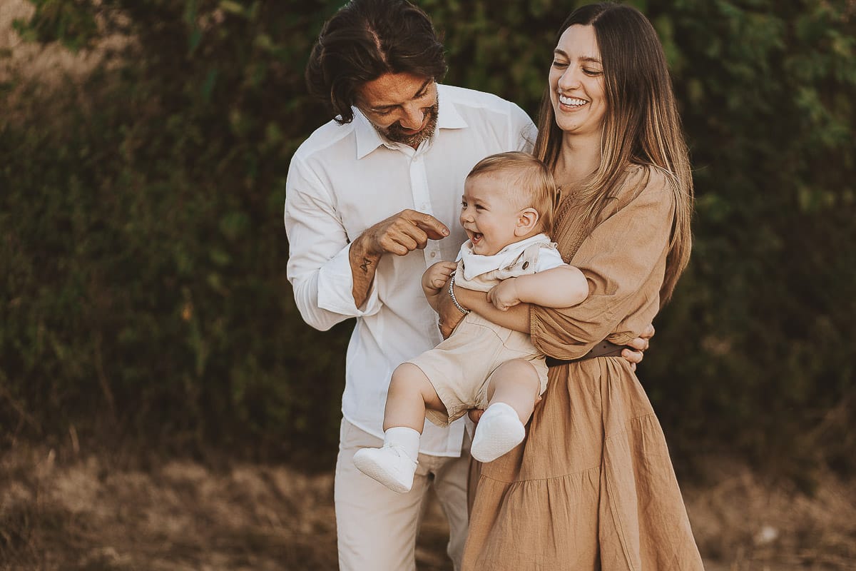 Servizio fotografico di famiglia a Torino: un tramonto dorato a Mombello di Torino. Chiara, Alessandro e il piccolo Leonardo camminano in un vigneto