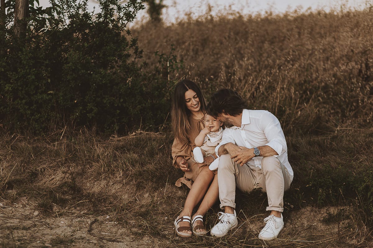 Servizio fotografico di famiglia a Torino: un tramonto dorato a Mombello di Torino. Chiara, Alessandro e il piccolo Leonardo seduti ai bordi di un campo di grano.